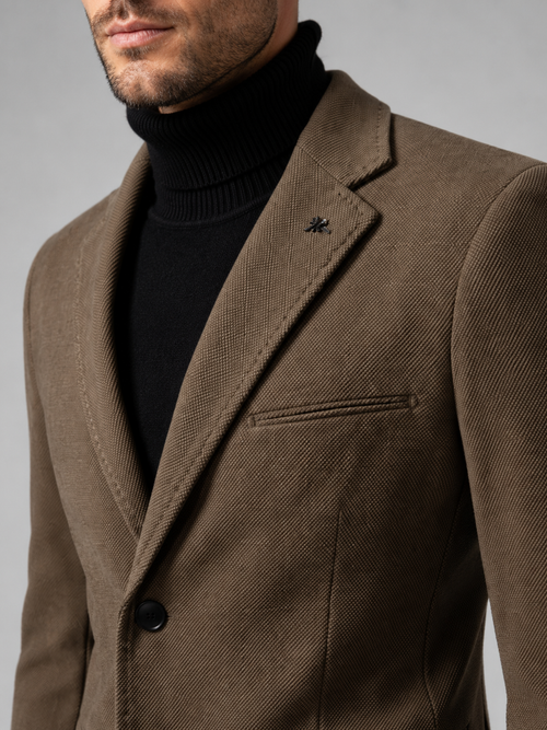Close up of brown blazer showing tailored construction, notch lapel, and single breasted button detail