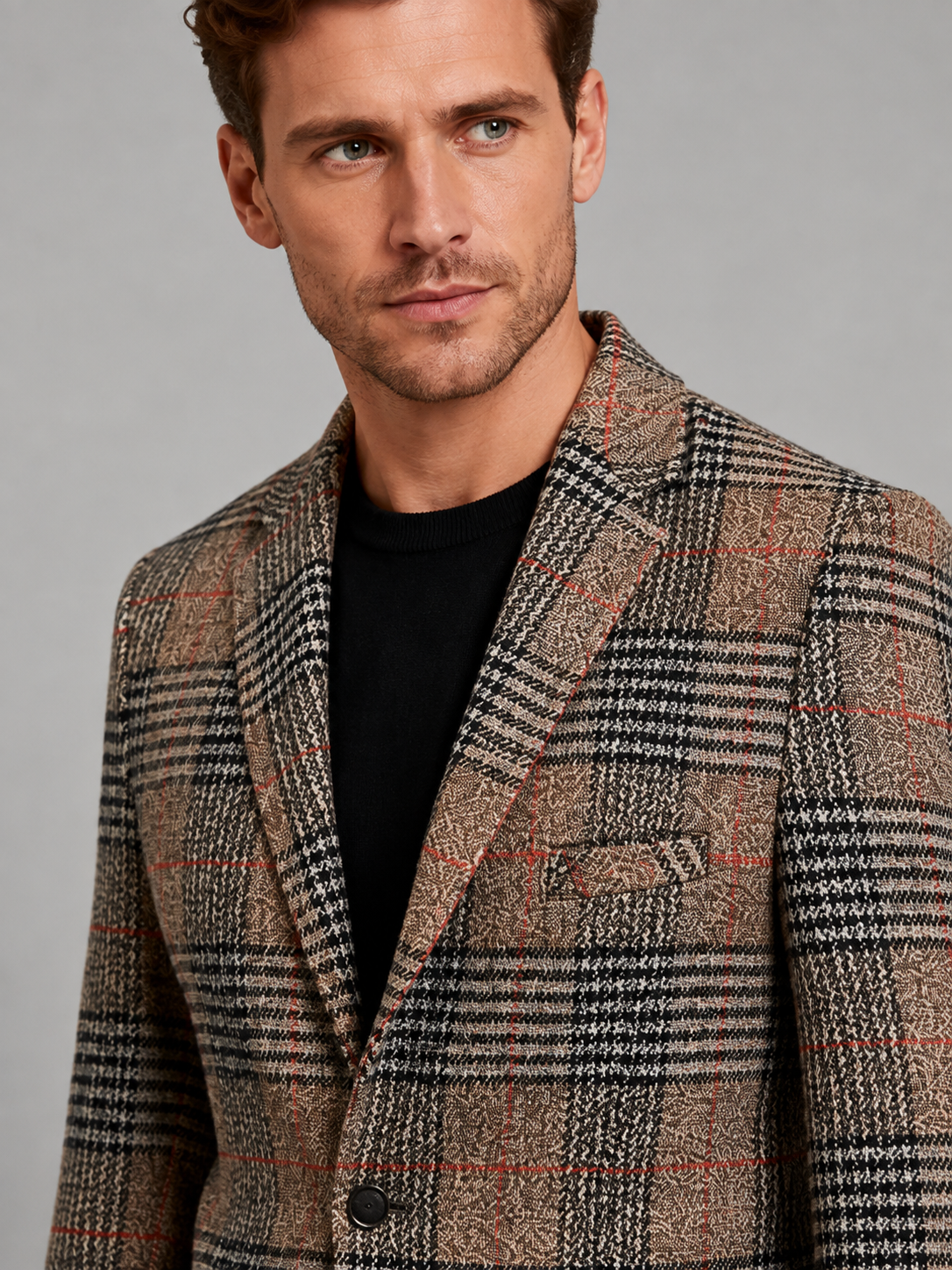 Close-up of a brown checkered blazer showing the woven check pattern, notched lapel, button closure, premium fabric texture, and tailored stitching