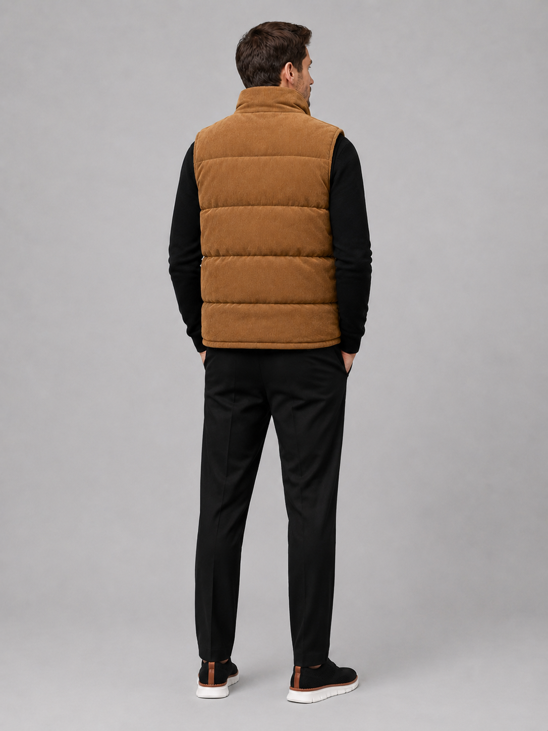 Back view of a man wearing a brown corduroy puffer vest showing the sleeveless cut, padded construction, and comfortable fit