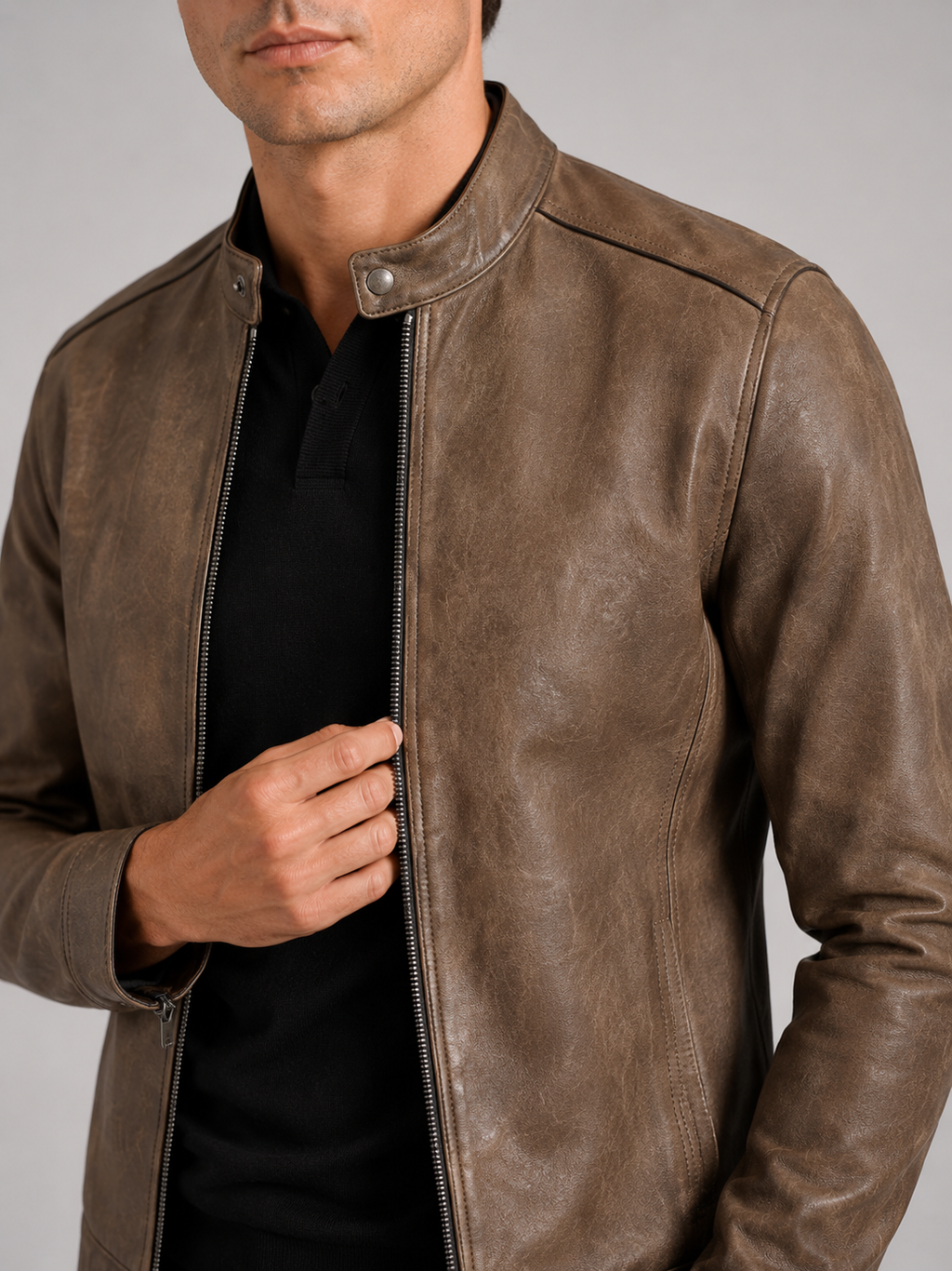 Close up of brown leather moto jacket showing smooth leather texture and stand collar zipper detail