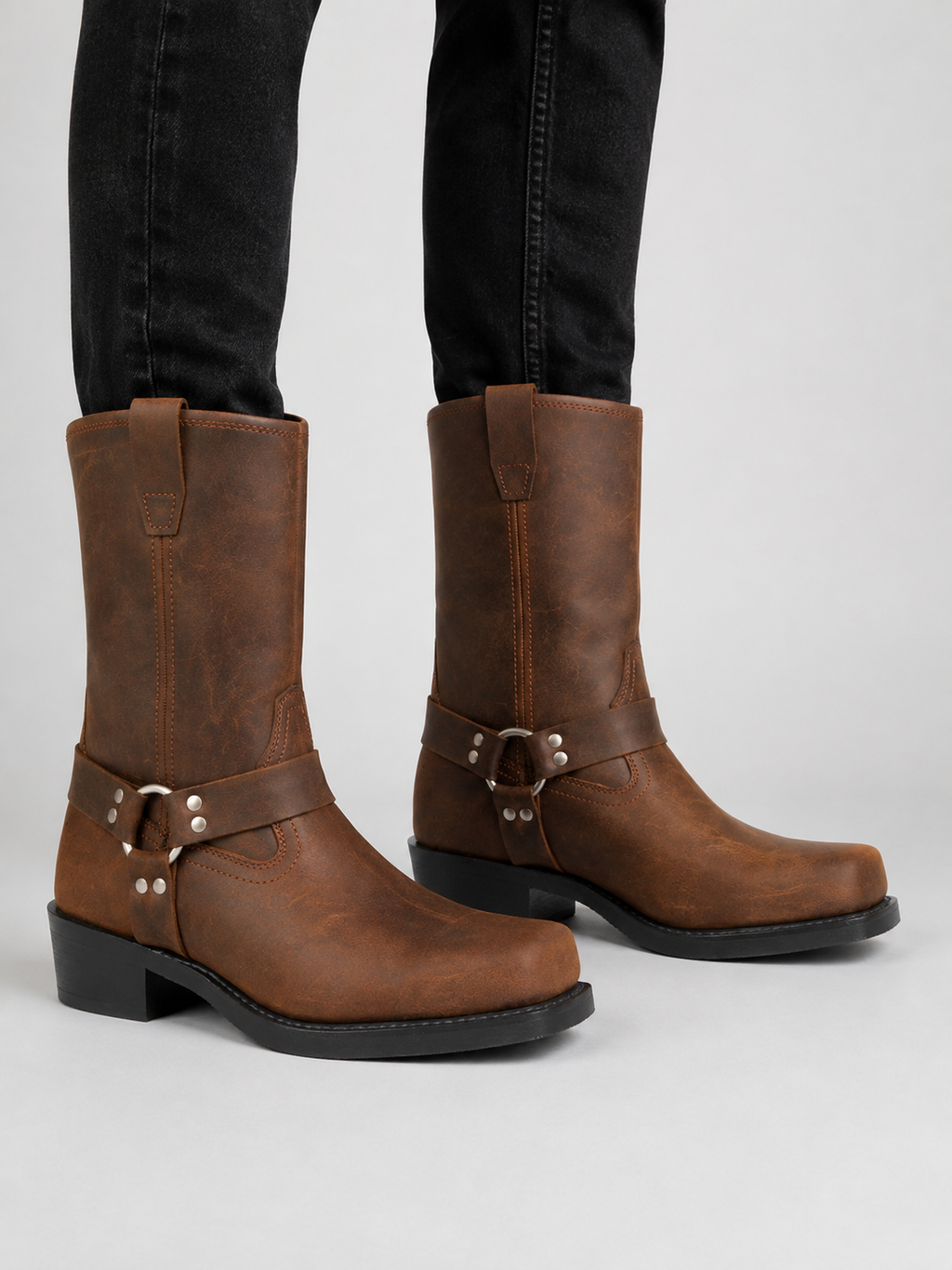 Man wearing brown men’s mid calf cowboy boots with a leather upper and slip-on western design in a casual everyday outfit
