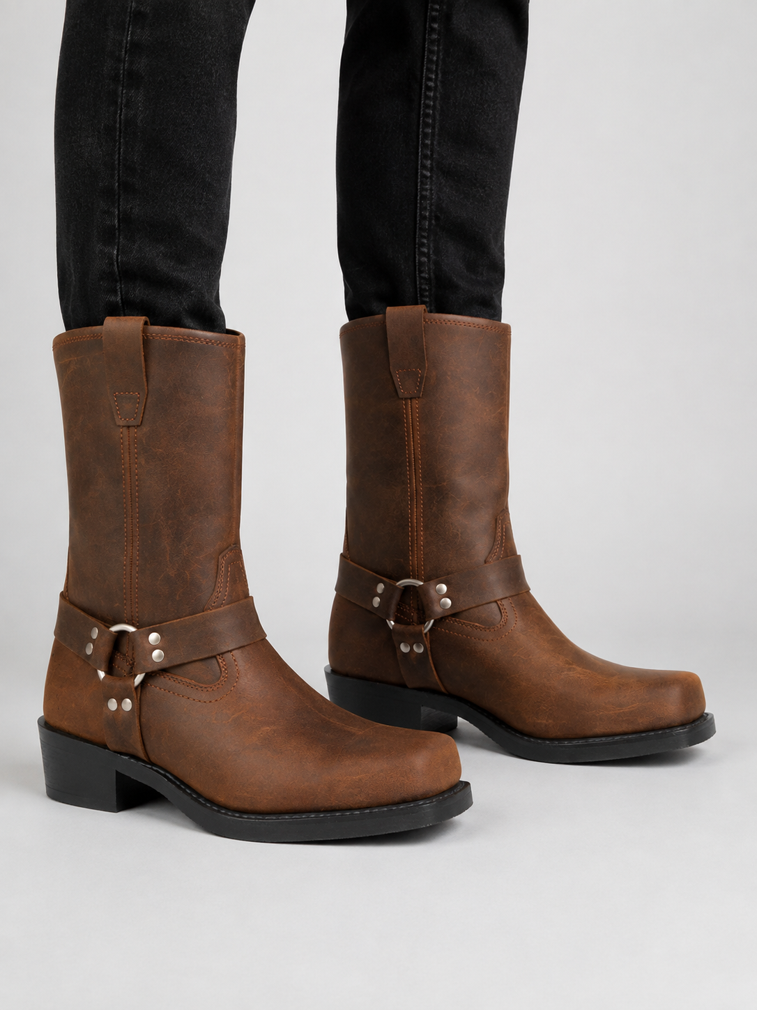 Man wearing brown men’s mid calf cowboy boots with a leather upper and slip-on western design in a casual everyday outfit