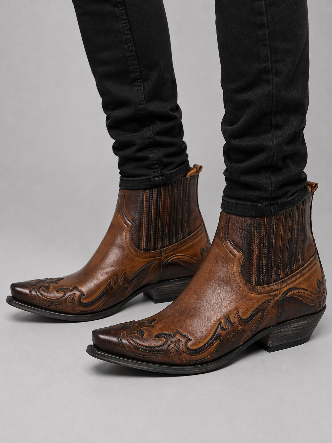 Man wearing brown western cowboy boots with embroidered leather and pointed toe in a casual everyday outfit