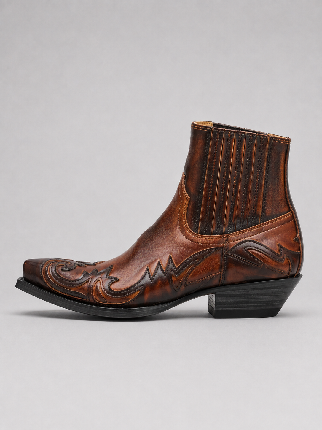 Side view of brown men’s western cowboy boots showing embroidered leather upper, pointed toe, stacked heel, and ankle boot silhouette