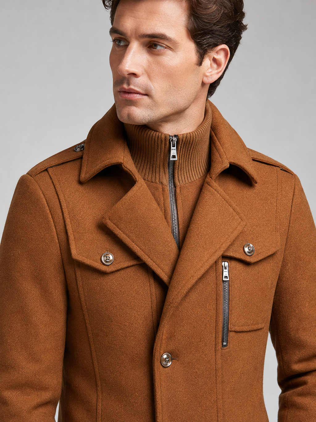 Close-up of a brown wool overcoat showing the double collar, warm fabric texture, button closure, cuffs, pockets, and tailored stitching