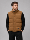 Front view of a man wearing a brown corduroy puffer vest with a stand collar, padded construction, and full zip front