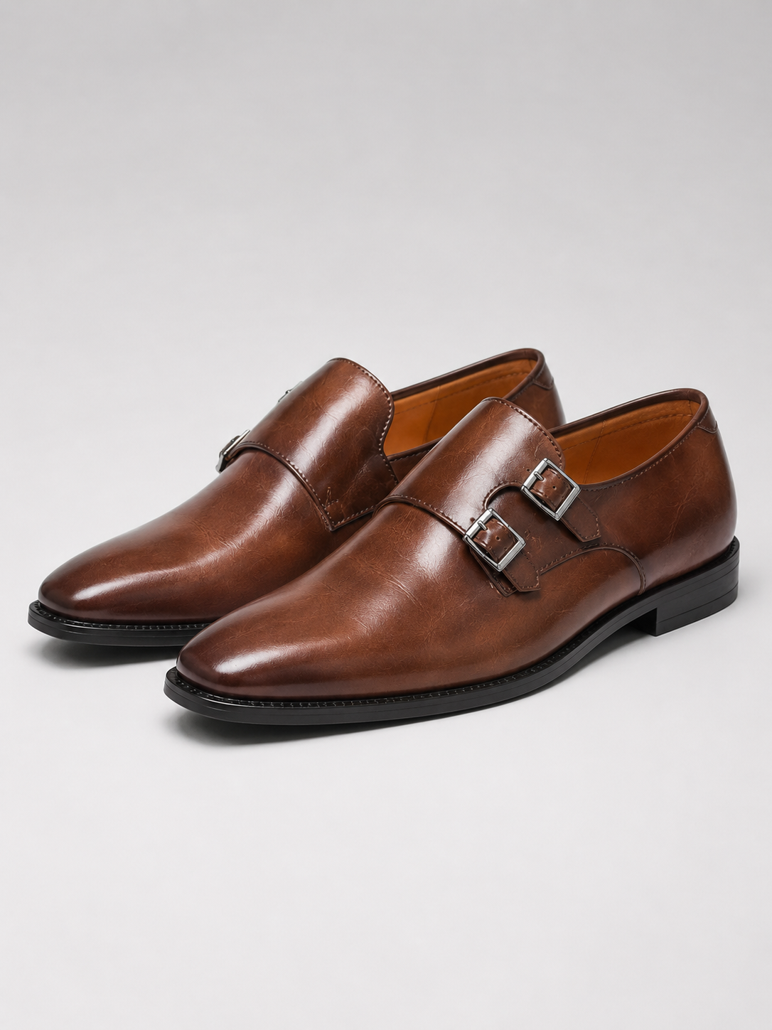 Close up of brown leather monk strap shoes showing polished finish and pointed toe detail