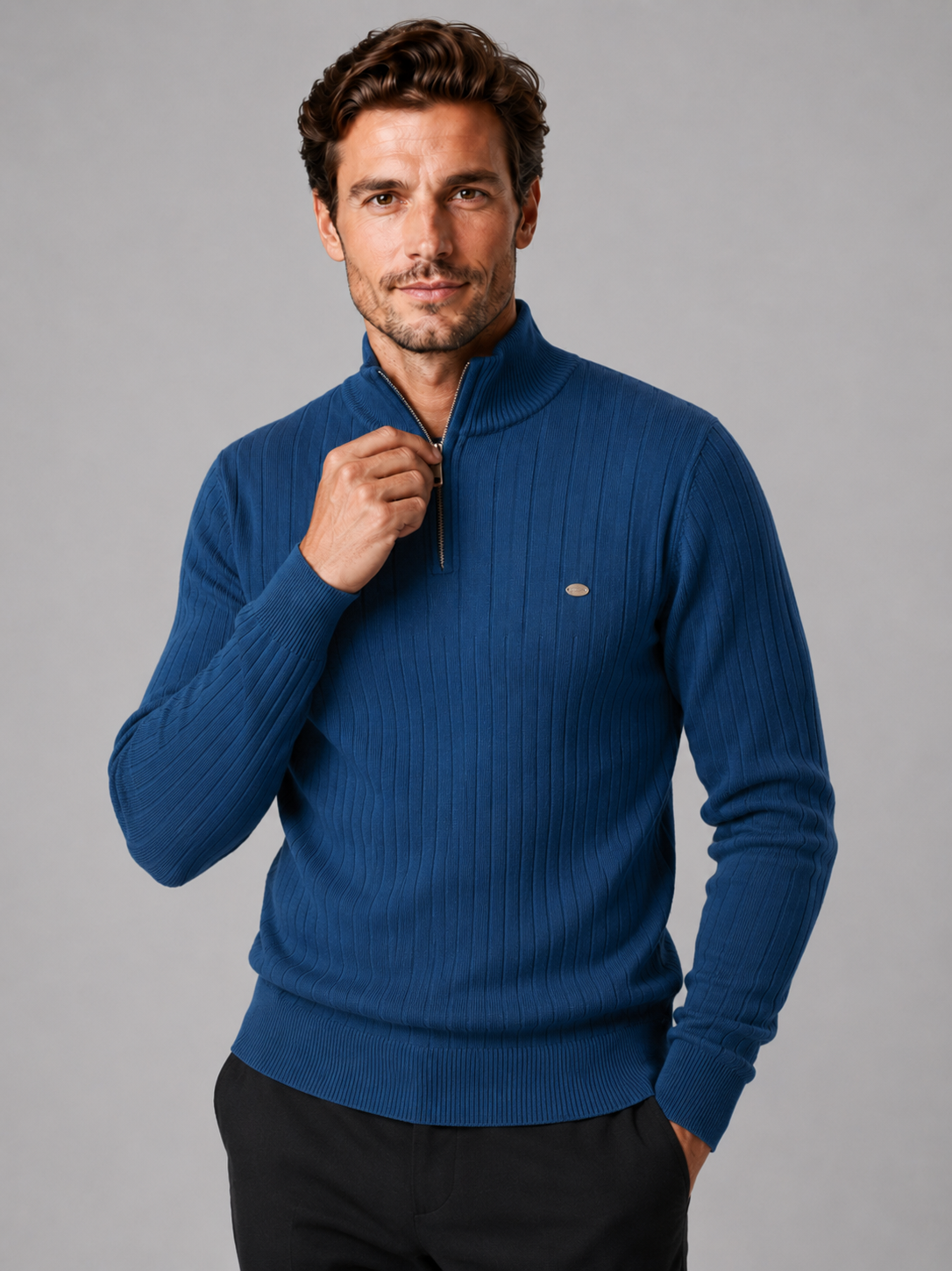 Close-up of a denim blue quarter zip pullover sweater showing the cotton knit texture, stand collar, zipper placket, cuffs, hem, and stitching details