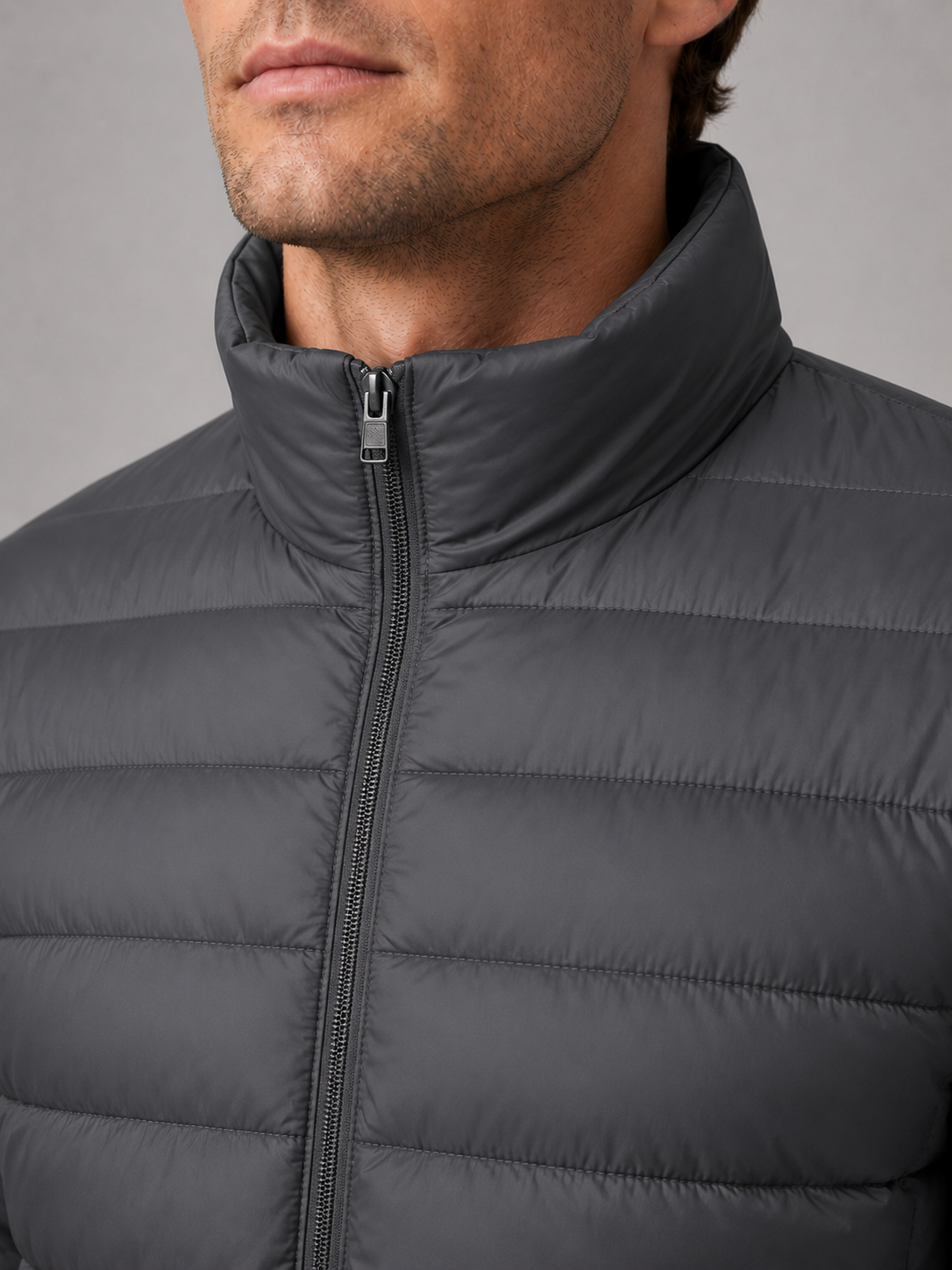 Close up of granite down puffer jacket showing insulated quilting, stand collar, and weather resistant fabric detail