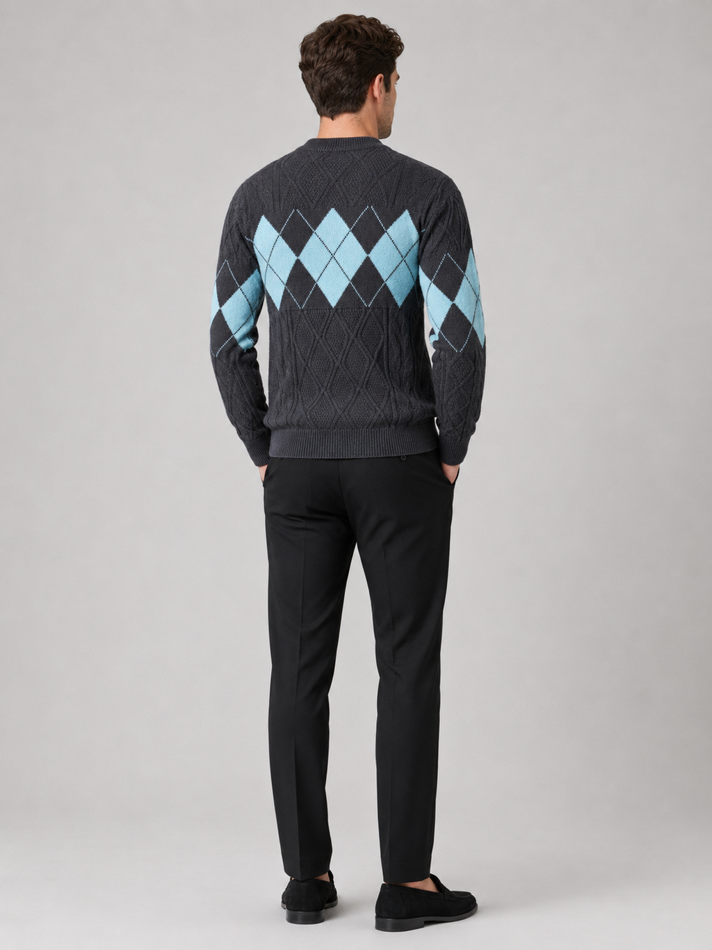 Back view of a man wearing a gray argyle cable knit sweater showing the mock neck, long sleeves, thick knit fabric, and comfortable fit
