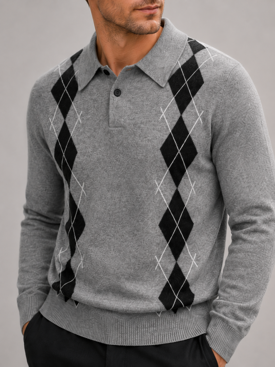 Close-up of a gray argyle sweater showing the plaid knit pattern, contrast collar, ribbed cuffs, hem, and premium knit texture
