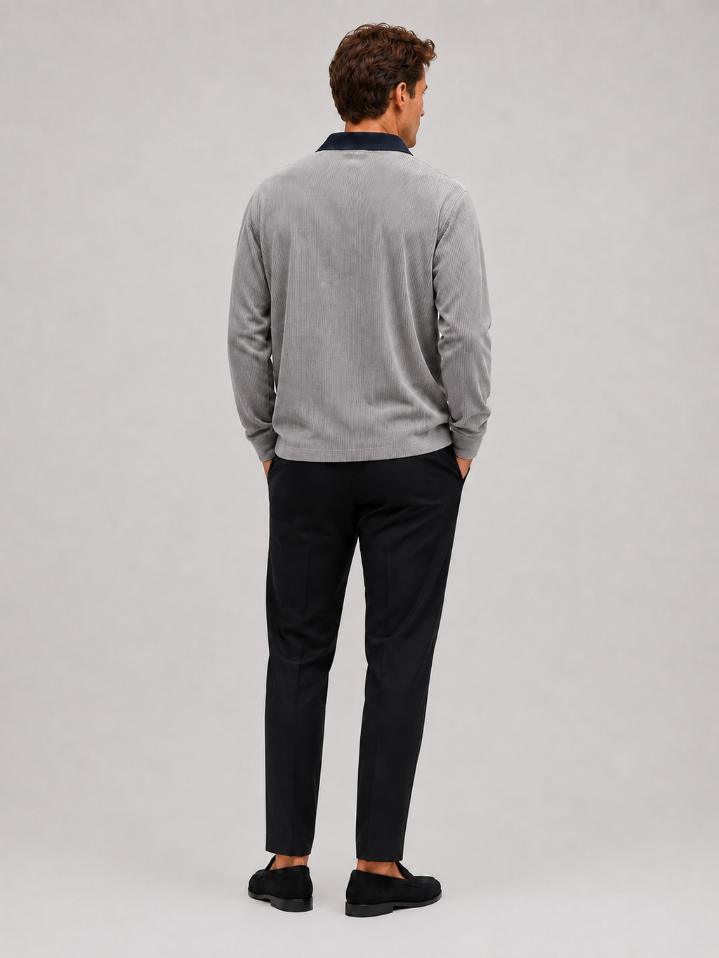 Back view of a man wearing a gray corduroy polo shirt showing the long sleeves, relaxed fit, and soft textured fabric