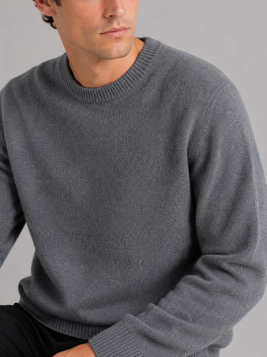 Close up of gray knit sweater showing soft textured fabric and classic crew neck detail