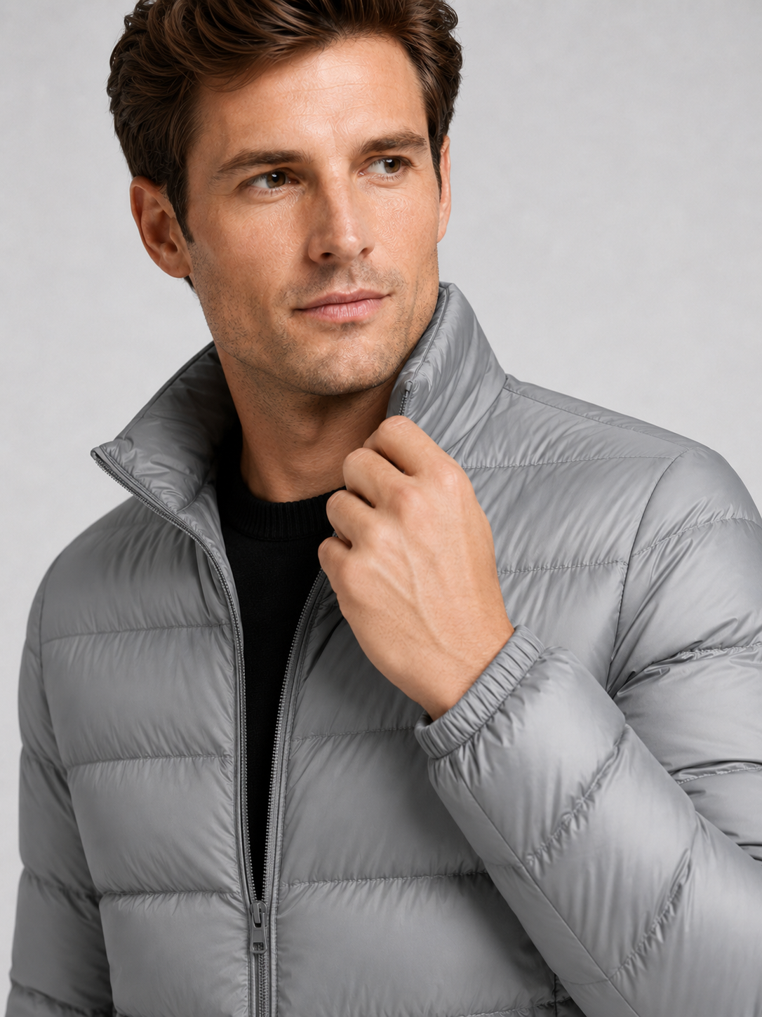 Close up of gray down jacket showing lightweight quilted insulation, stand collar, and weather resistant fabric detail