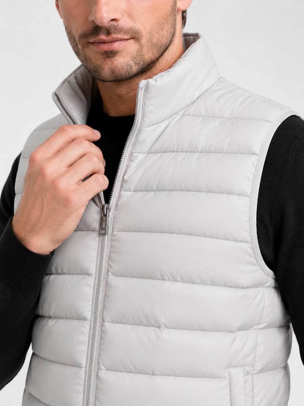 Close up of light gray down puffer vest showing thick quilted insulation, zip up front, and weather resistant fabric detail