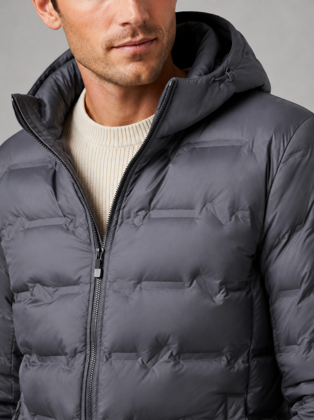 Close up of gray duck down jacket showing lightweight quilted insulation, attached hood, and weather resistant fabric detail