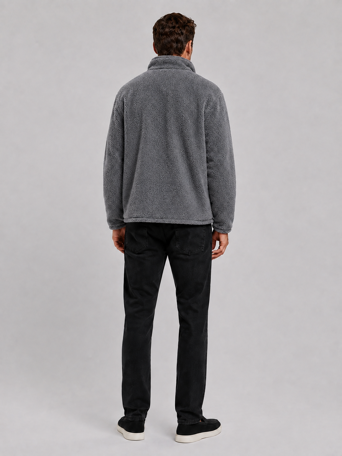 Back view of a man wearing a gray fleece jacket showing the relaxed loose fit, long sleeves, stand collar, and soft fleece construction