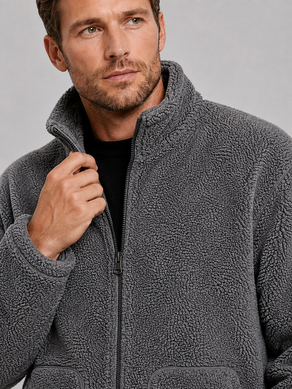 Close-up of a gray fleece jacket showing the soft fleece texture, full zipper, stand collar, pockets, cuffs, hem, and stitching details
