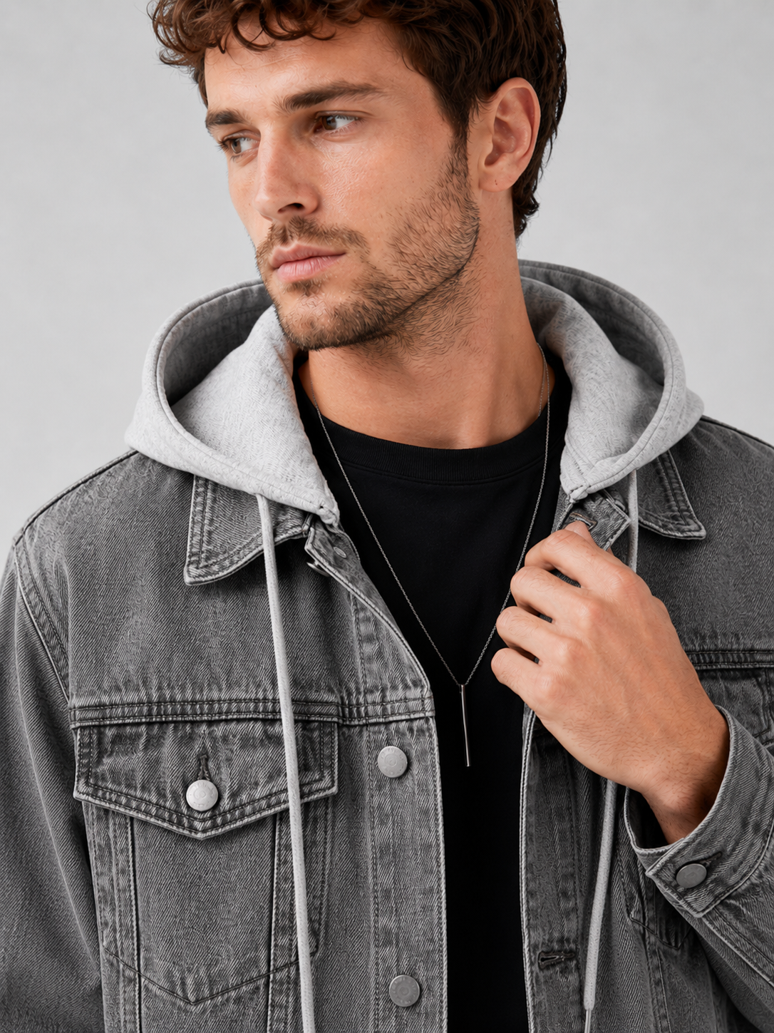 Close up of gray denim jacket showing washed fabric texture, detachable hood, and stitching detail
