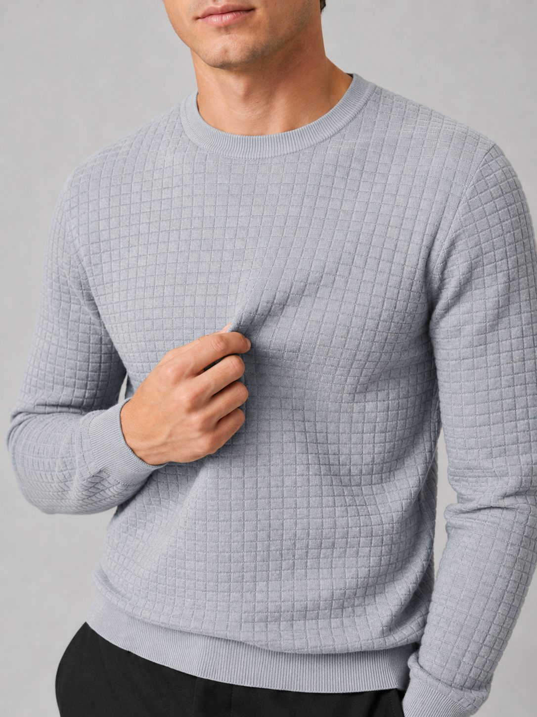 Close up of gray jacquard sweater showing textured knit pattern and classic crew neck detail