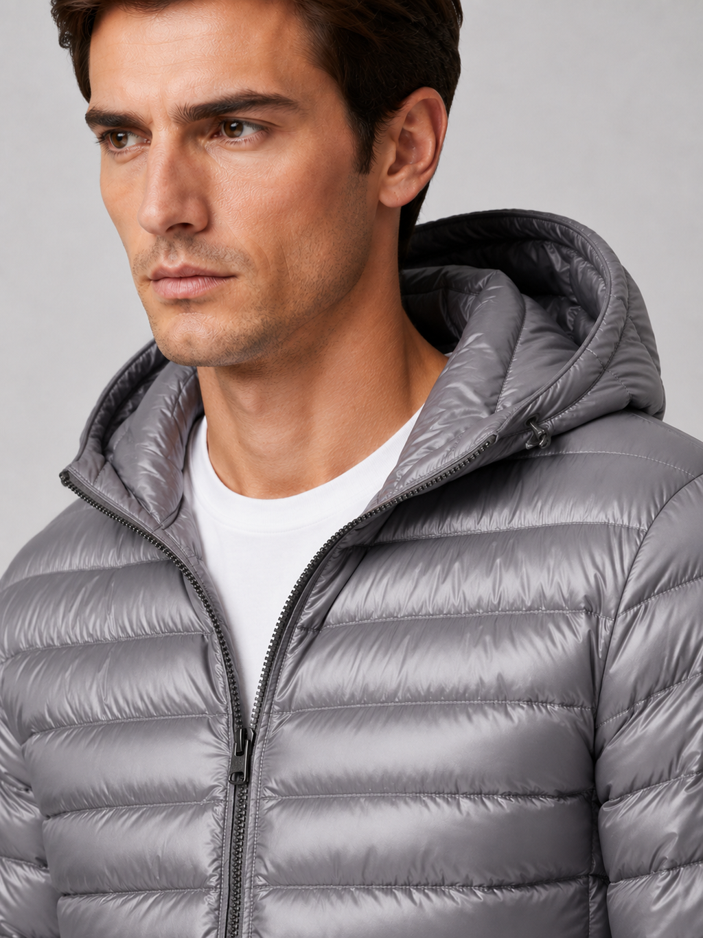 Close up of gray hooded down jacket showing lightweight quilted insulation, attached hood, and weather resistant fabric detail