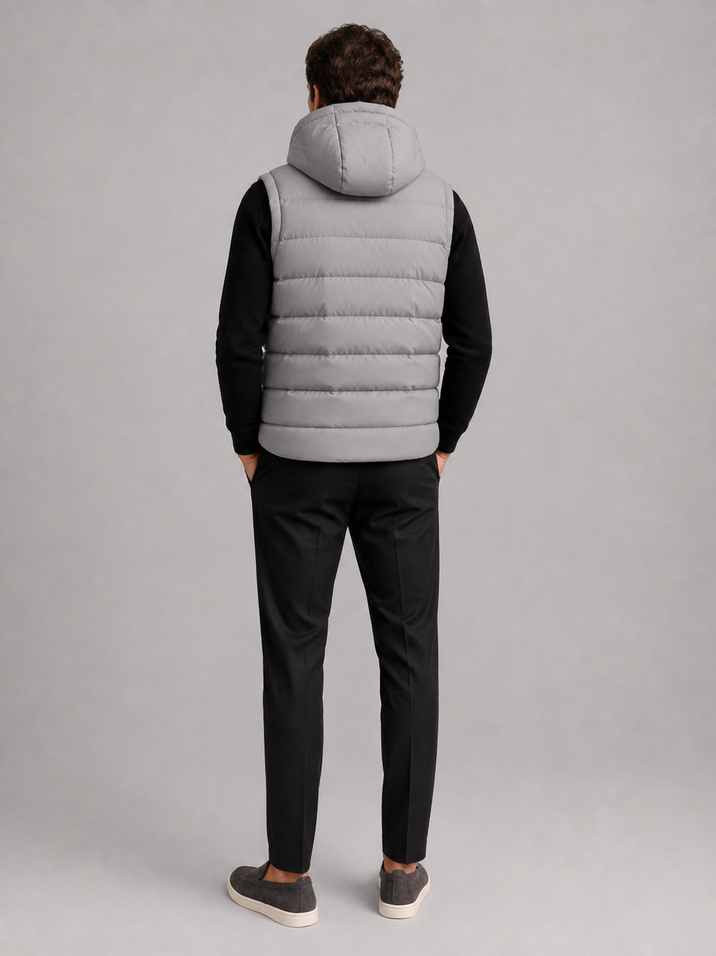Back view of a man wearing a gray hooded puffer vest showing the attached hood, padded construction, sleeveless cut, and comfortable fit