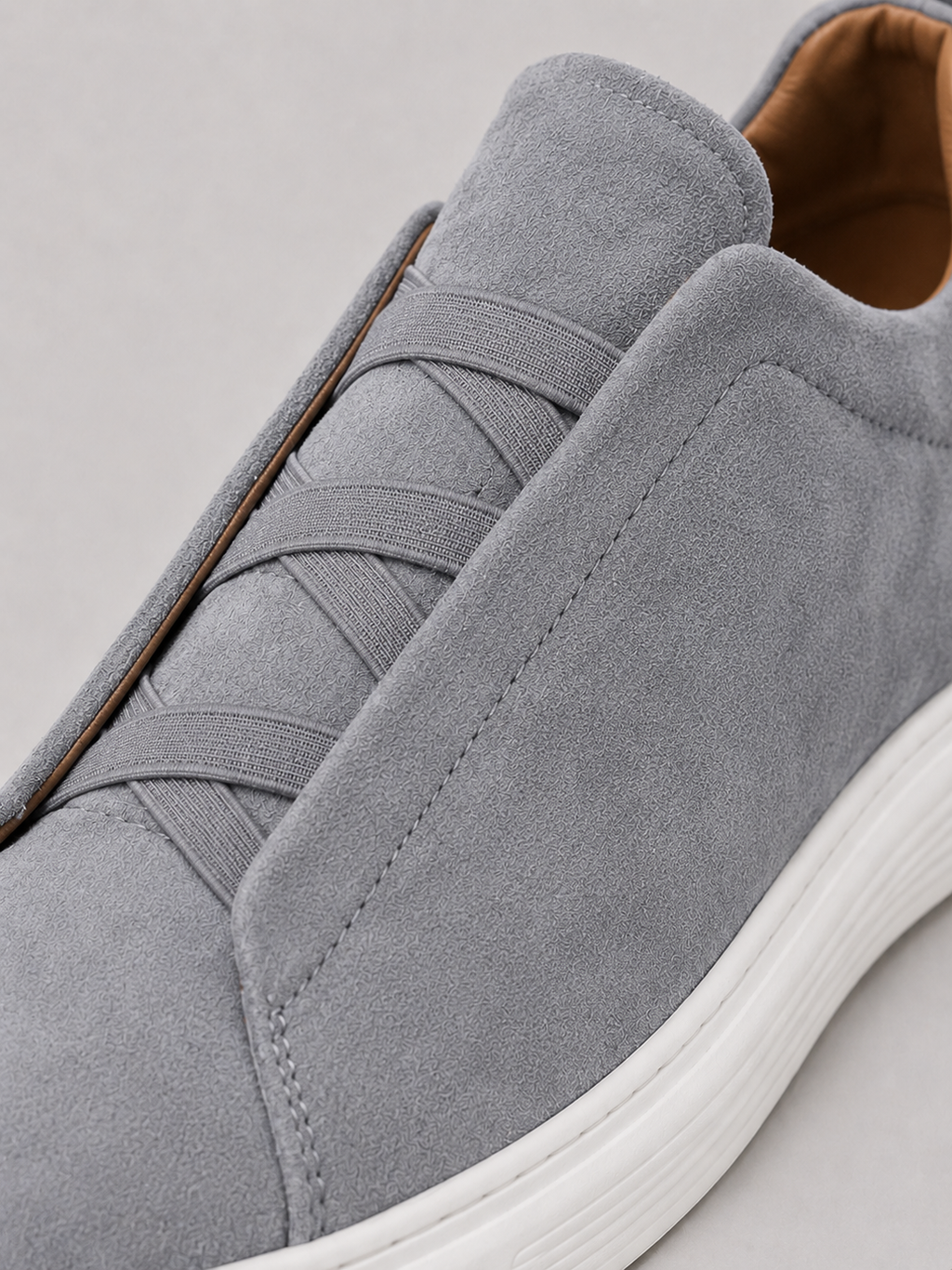 Close up of gray suede slip on sneakers showing soft suede texture and clean stitching detail