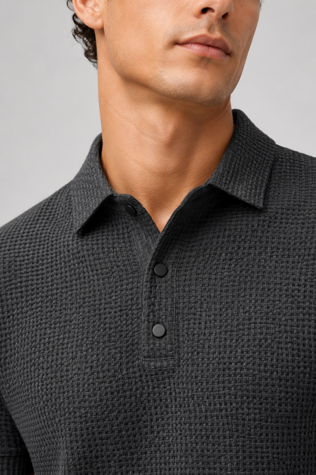 Close up of gray textured knit polo fabric showing breathable weave and button placket detail