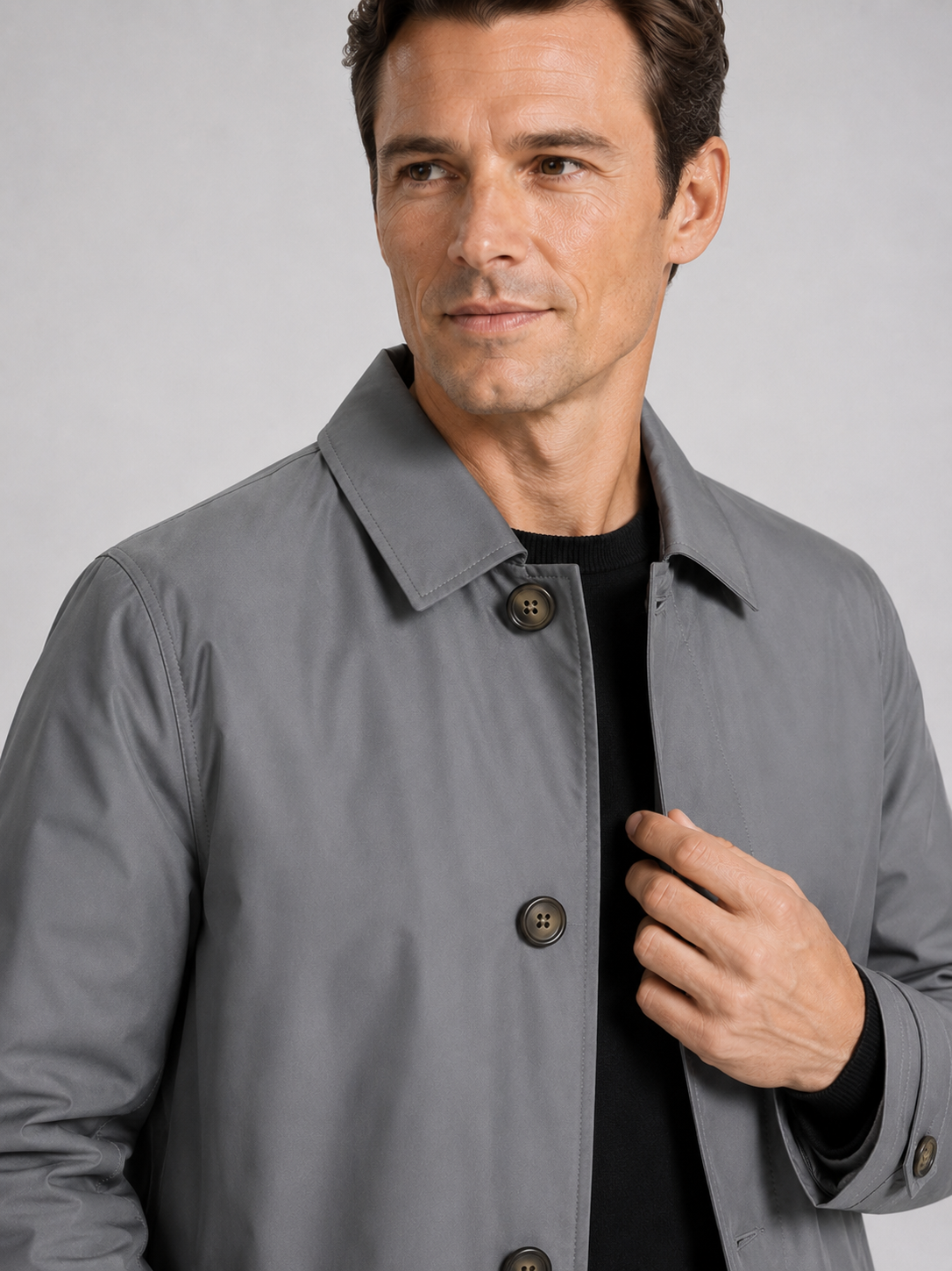 Close up of gray trench coat showing structured lapel, button up front, and premium fabric detail