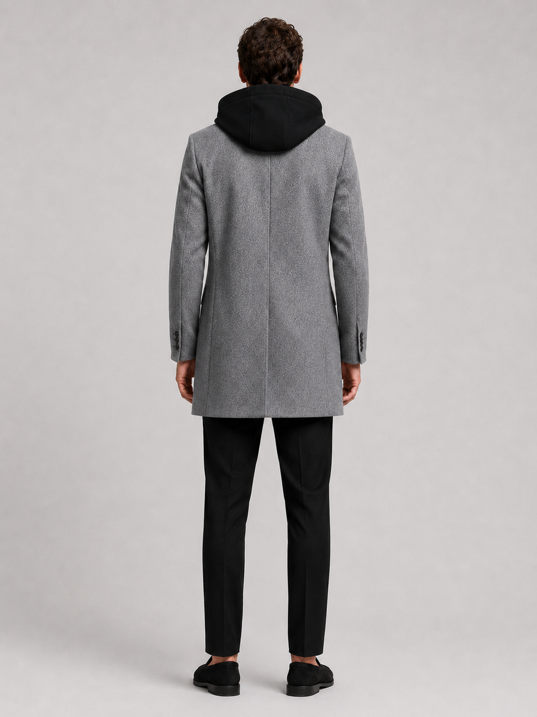 Backside photo of a man wearing a gray wool hooded trench coat, showing the hood, back seam, coat length, and tailored winter fit