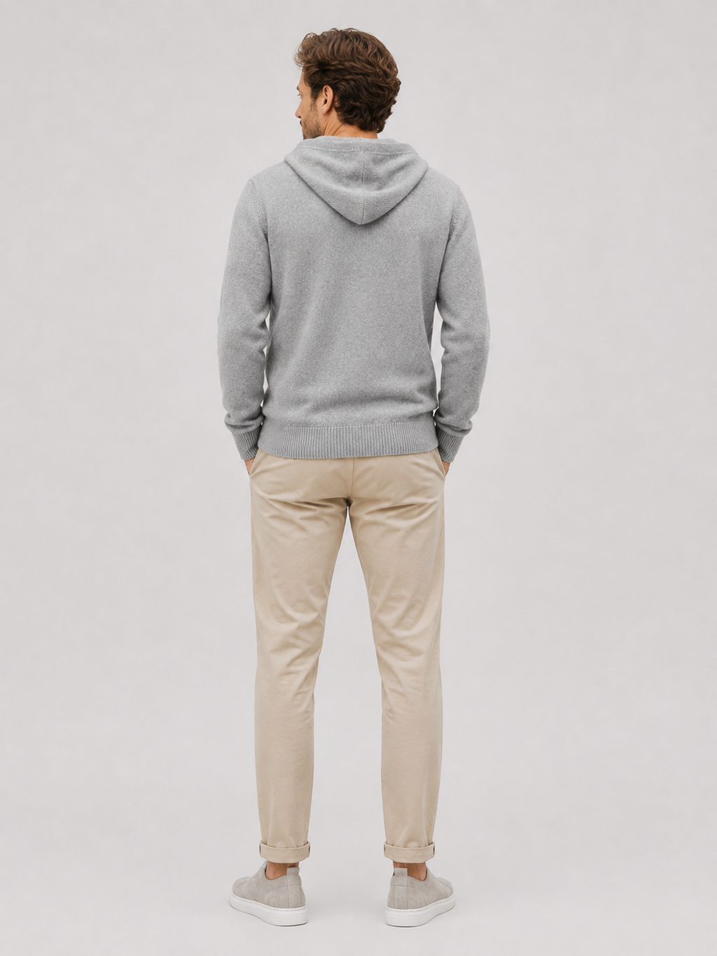 Back view of a man wearing a gray wool cardigan sweater showing the attached hood, thick knit texture, long sleeves, and comfortable fit
