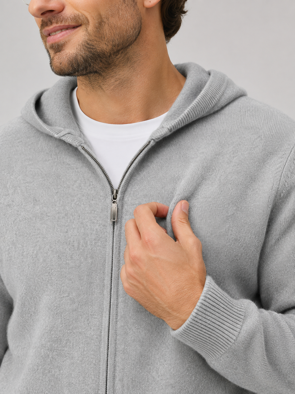 Close-up of a gray wool cardigan hoodie showing the thick knit texture, full zipper, hood, ribbed cuffs, hem, pockets, and stitching