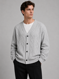 Front view of a man wearing a gray cable knit cardigan sweater with a V-neck, diamond pattern, button-front design, and oversized fit