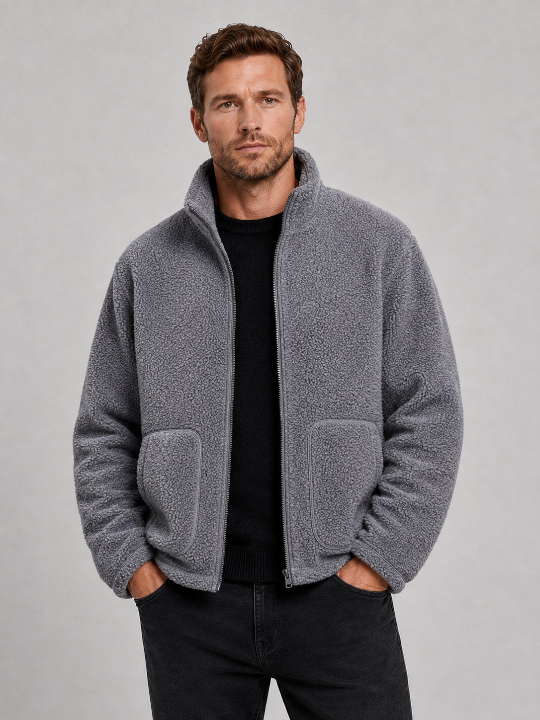 Front view of a man wearing a gray full zip fleece jacket with a stand collar, loose fit, long sleeves, and warm fall winter design