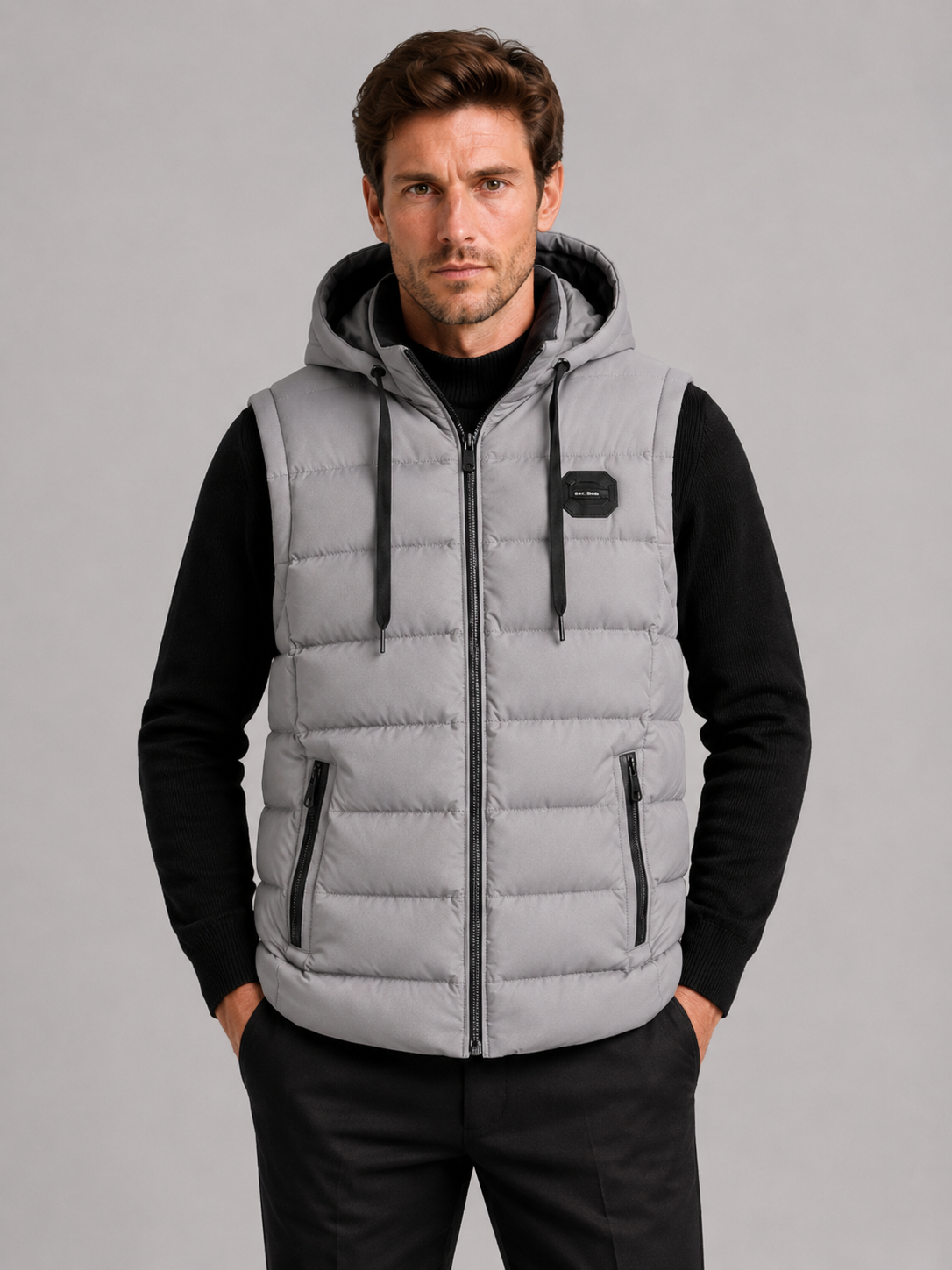 Front view of a man wearing a gray hooded puffer vest with cotton padding, thick insulation, sleeveless design, and full zip front