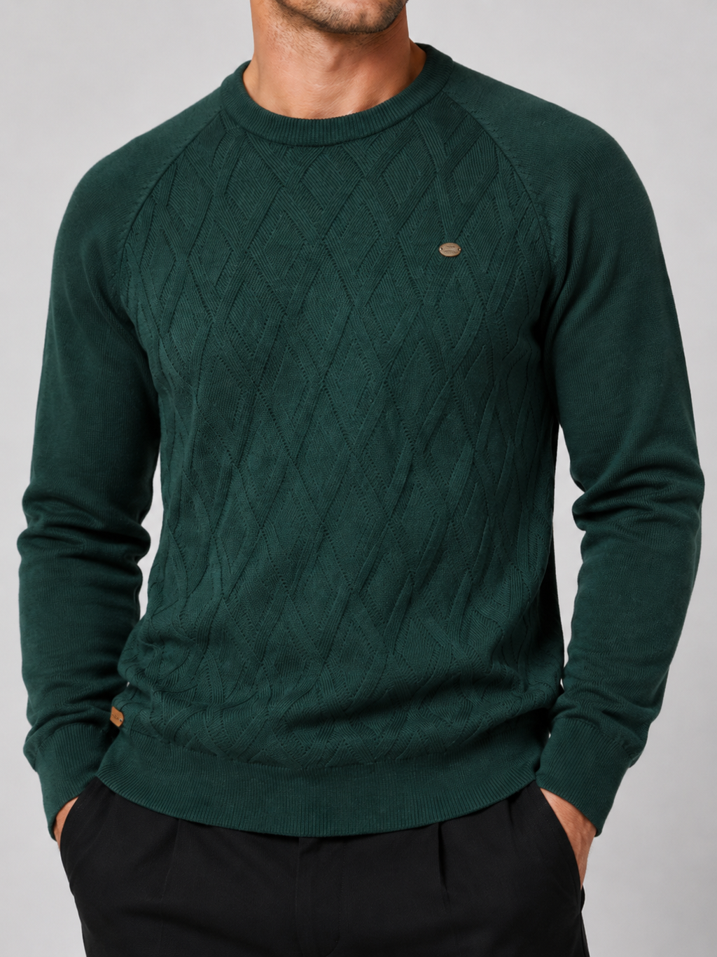 Close-up of a green argyle sweater showing the diamond knit pattern, crew neckline, ribbed cuffs, hem, and warm texture