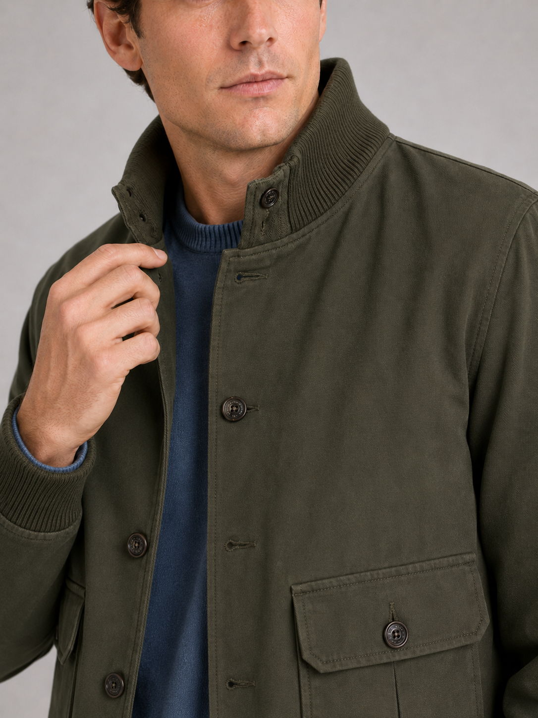 Close up of green cargo jacket showing patchwork design, ribbed trim, and durable fabric detail