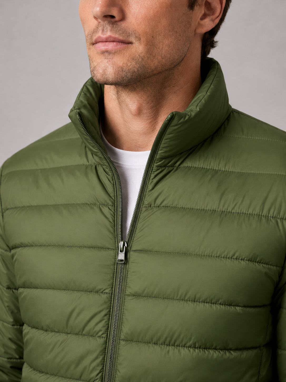 Close up of green down puffer jacket showing insulated quilting, stand collar, and weather resistant fabric detail