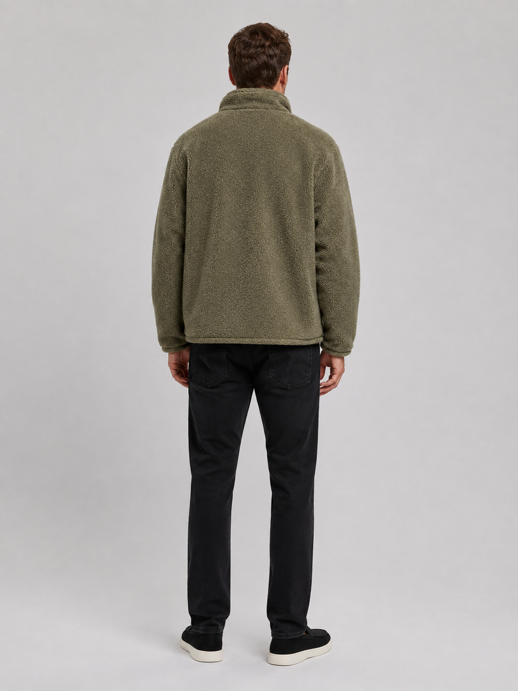 Back view of a man wearing a green fleece jacket showing the relaxed loose fit, long sleeves, stand collar, and soft fleece construction