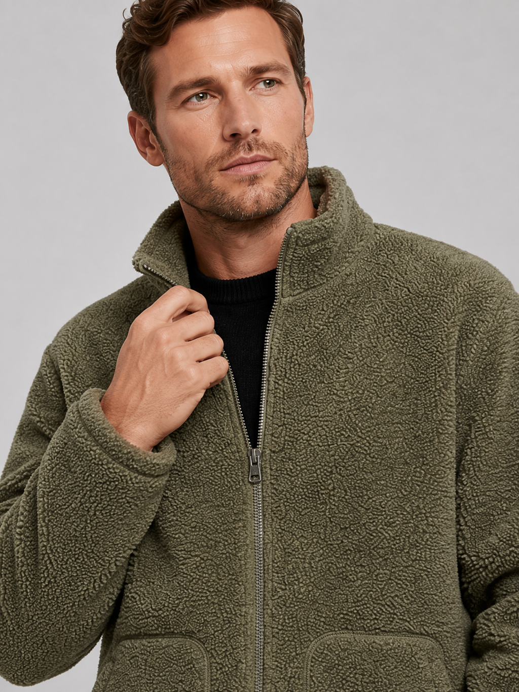 Close-up of a green fleece jacket showing the soft fleece texture, full zipper, stand collar, pockets, cuffs, hem, and stitching details
