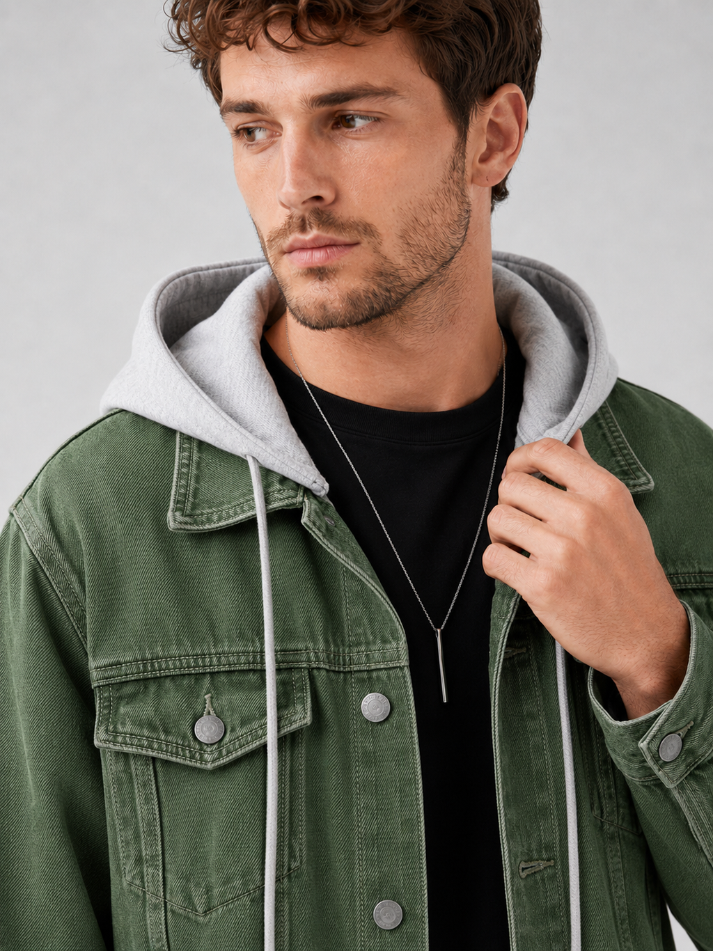 Close up of green denim jacket showing washed fabric texture, detachable hood, and stitching detail