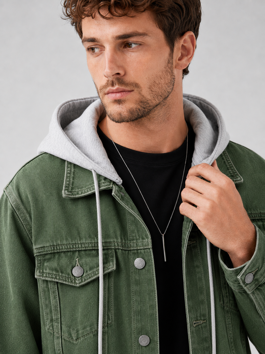 Close up of green denim jacket showing washed fabric texture, detachable hood, and stitching detail