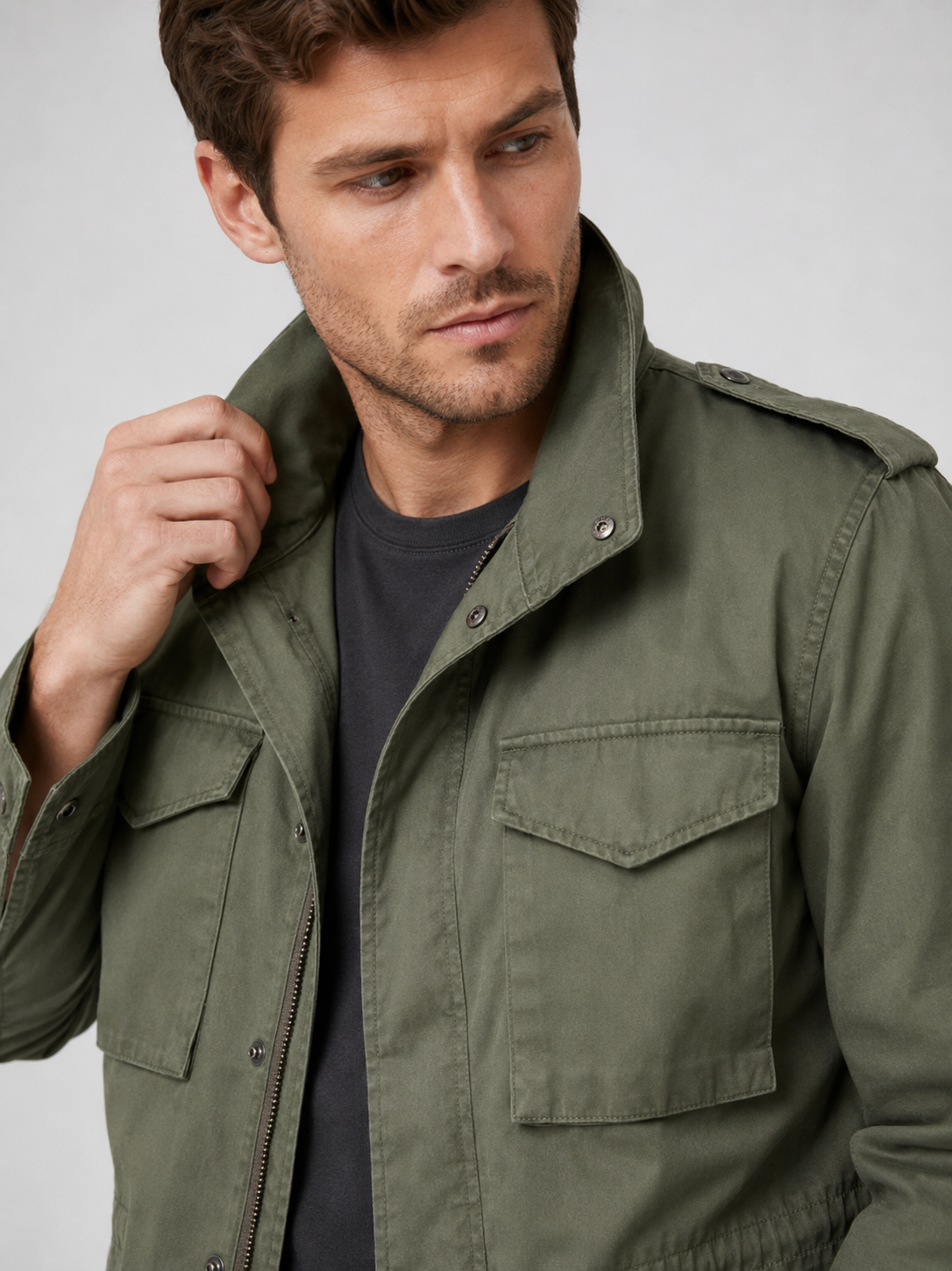 Close up of green military field jacket showing durable cotton fabric, utility pockets, and zip up front detail