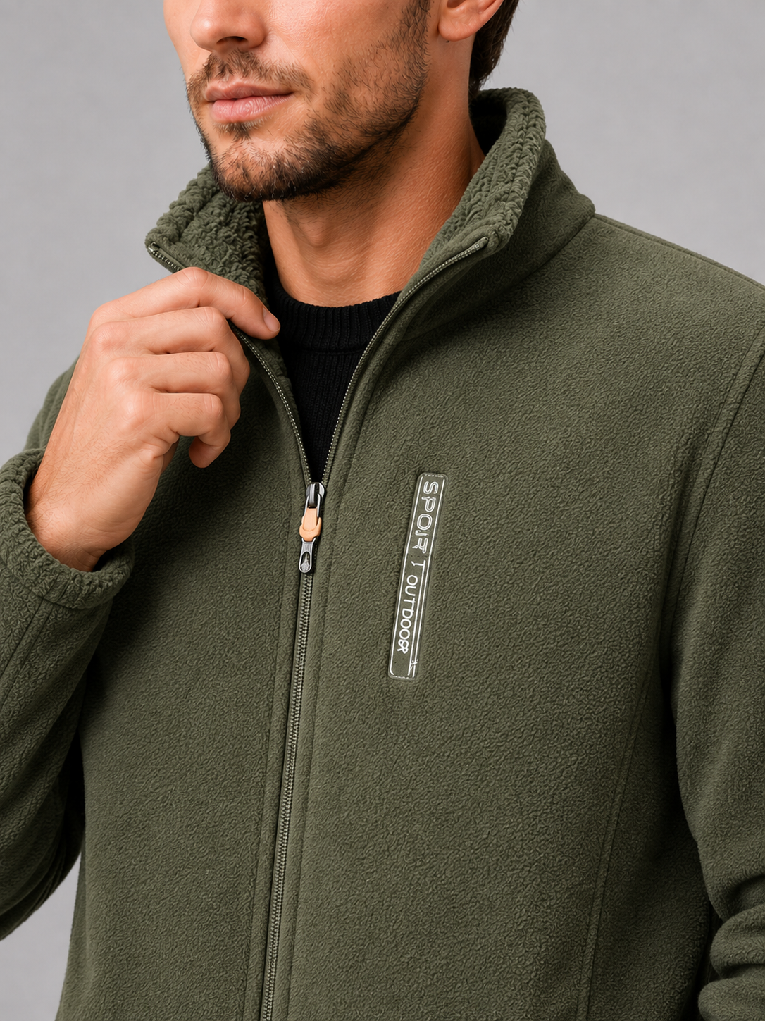 Close-up of a green polar fleece jacket showing the soft fleece texture, windproof construction, full zipper, stand collar, pockets, cuffs, and stitching details