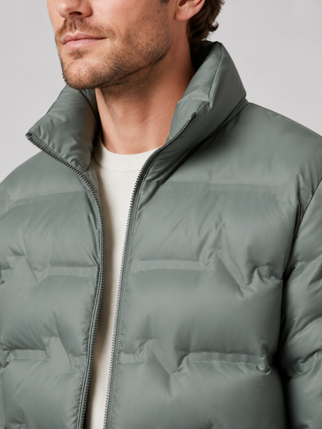 Close up of green white duck down jacket showing premium quilted insulation, stand collar, and weather resistant fabric detail