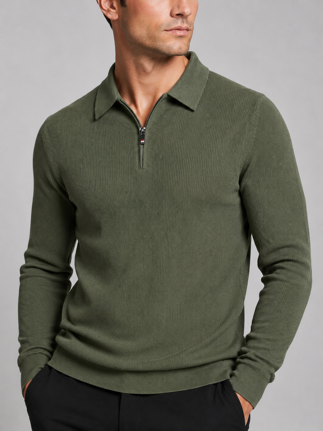 Close-up of a green quarter zip long sleeve polo showing the zipper closure, lapel collar, soft fabric texture, cuffs, hem, and stitching