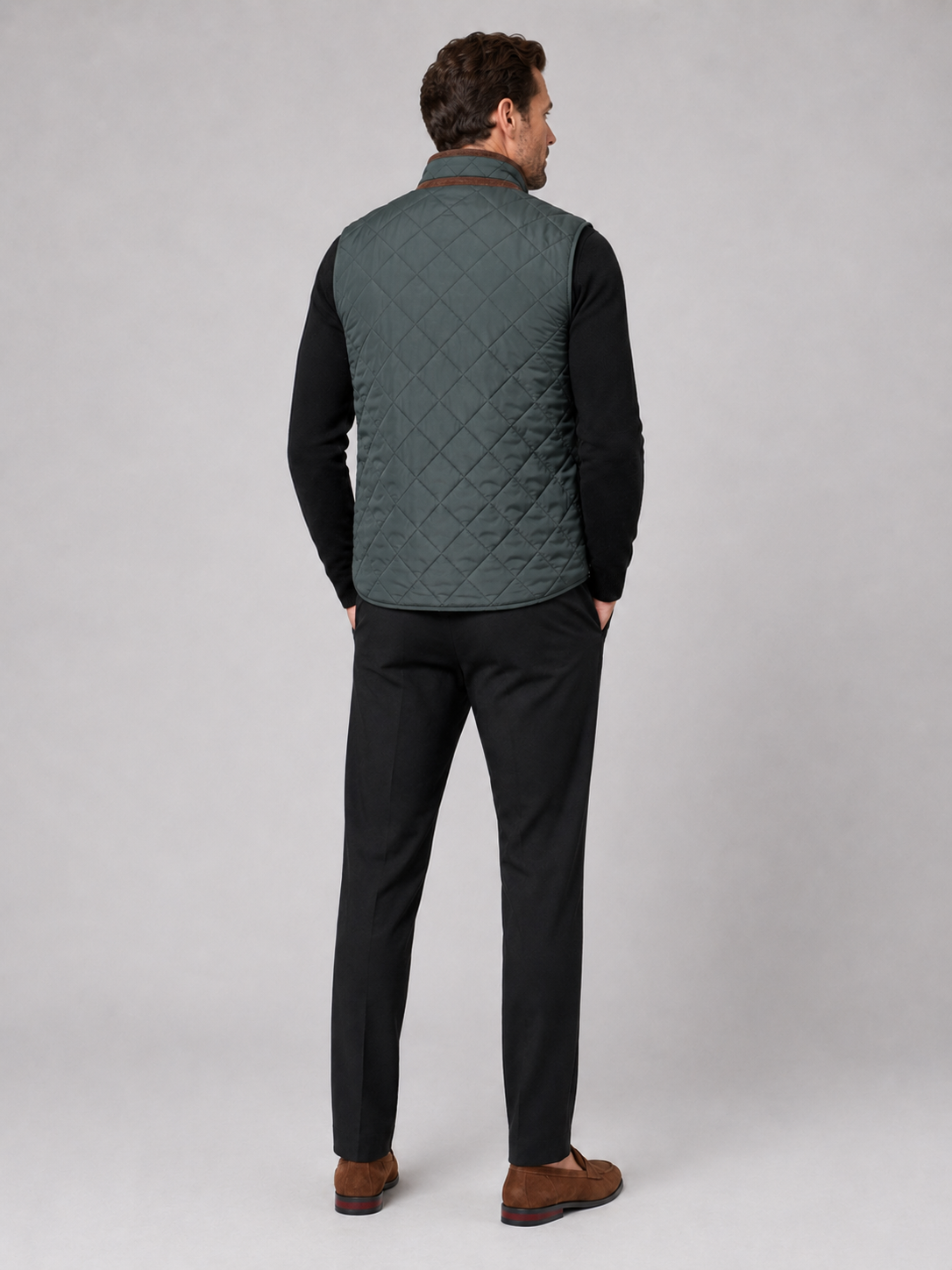Back view of a man wearing a green quilted vest showing the padded construction, sleeveless cut, and comfortable fit