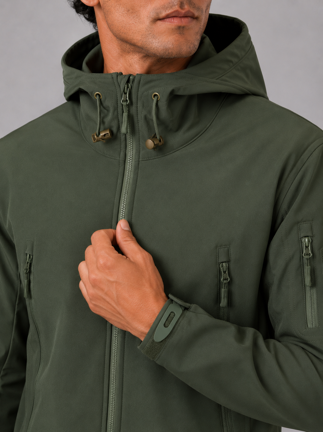 Close up of green tactical jacket showing waterproof soft shell fabric and hood detail