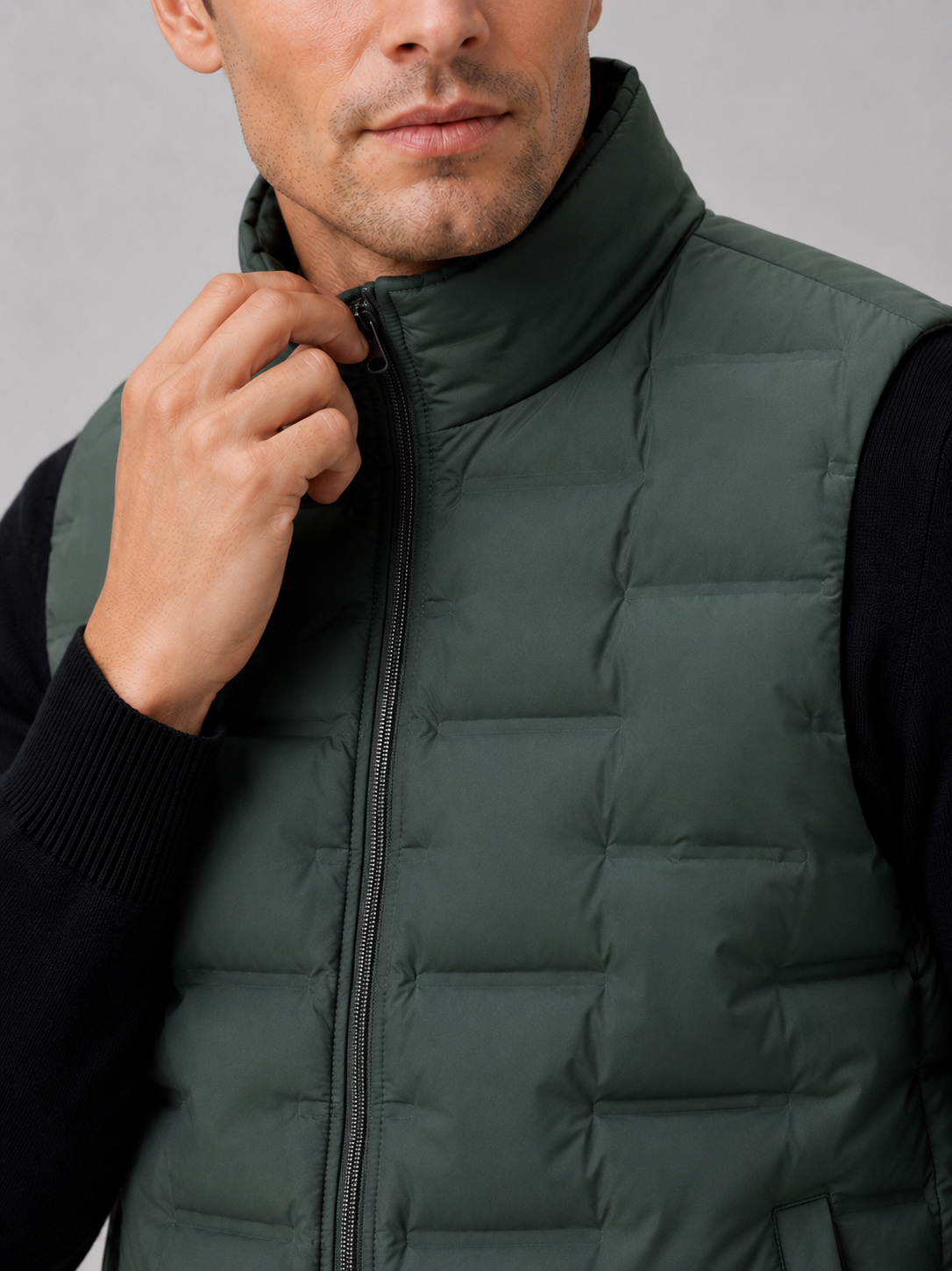 Close up of green white duck down vest showing lightweight quilted insulation, stand collar, and weather resistant fabric detail