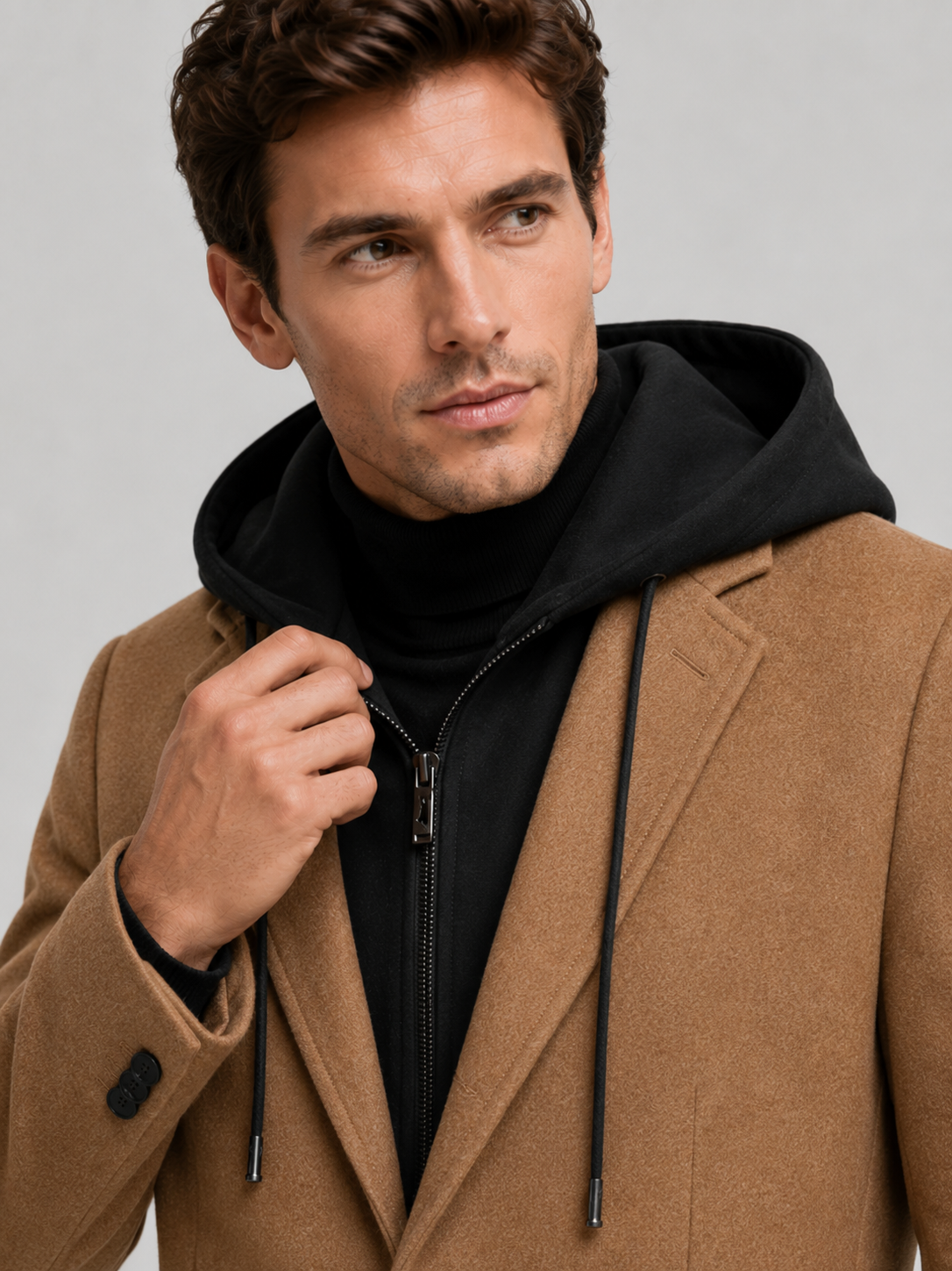 Detail photo of a man wearing a khaki wool hooded trench coat, close up of the wool texture, hood, collar, buttons, cuffs, and pocket construction